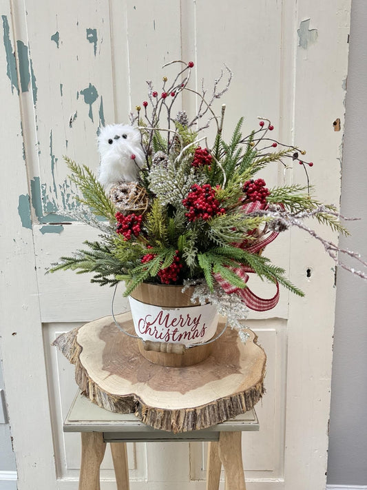 a rustic arrangement of mixed greens, berries and a white owl